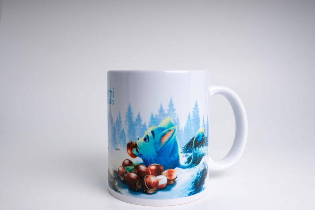 Mug cadeau original féerique PERYA LoomiStudio en céramique, fabrication artisanale suisse, création unique pleine de douceur. PERYA LoomiStudio avec Loomi donnant des noisettes à un écureuil en forêt enneigée